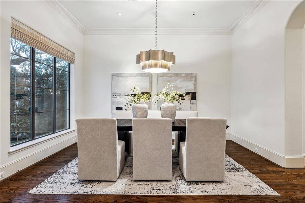 Elegant formal dining room featuring a stylish chandelier and large windows overlooking the front yard.