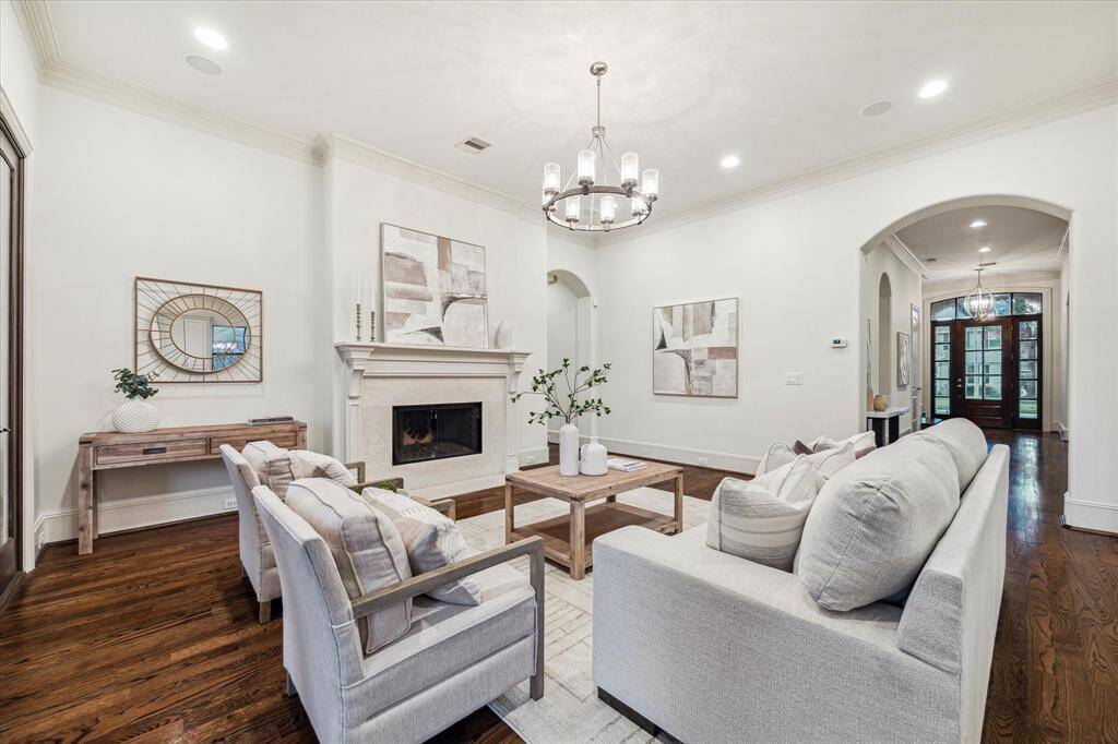 The living room boasts a cozy fireplace, built-in surround sound speakers and a chandelier, all seamlessly connected to the kitchen. The archway in the corner of the picture leads to the downstairs primary bedroom.