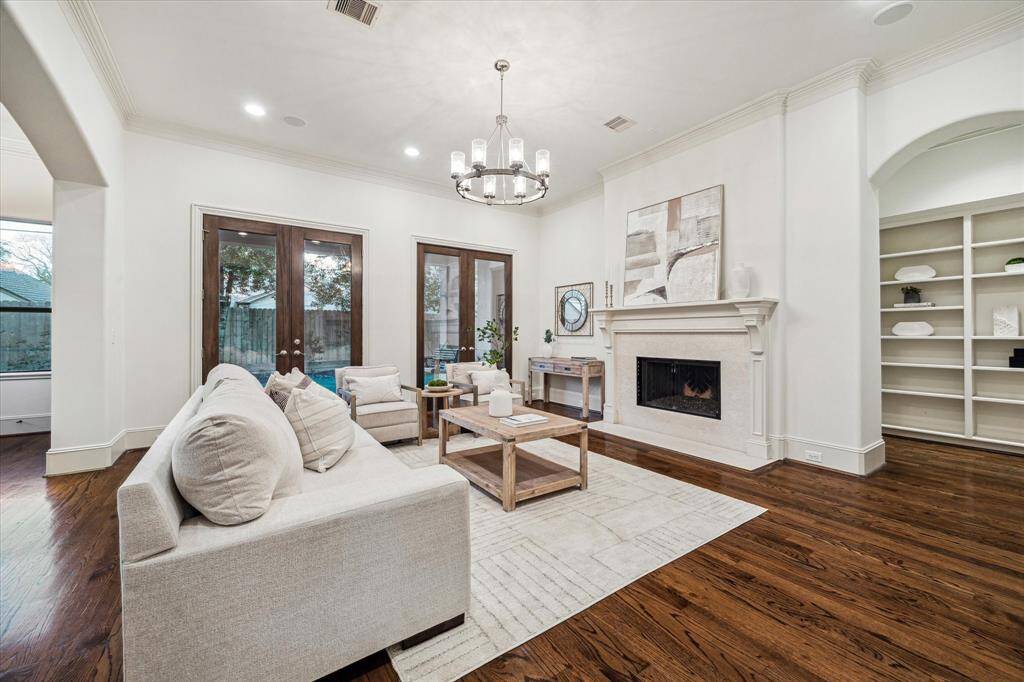 The living room features two sets of glass French doors that open to the covered porch and backyard, creating a seamless transition for indoor-outdoor entertaining.