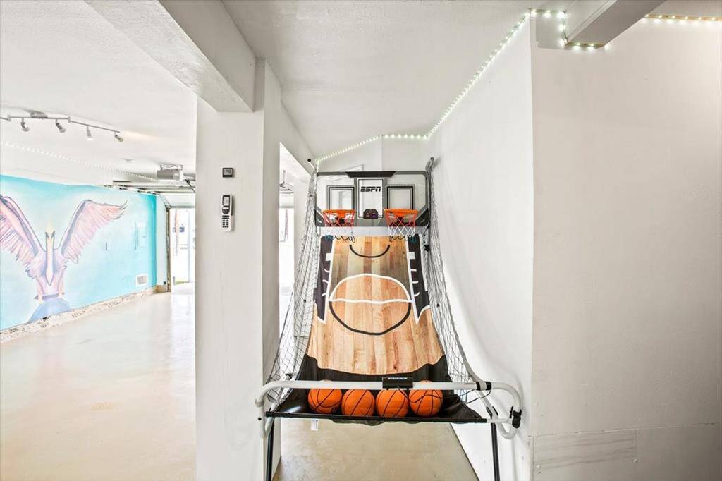 This photo shows a versatile indoor space with a basketball arcade game, adding a playful touch to the home. Bright lighting and artistic decor create a vibrant atmosphere.