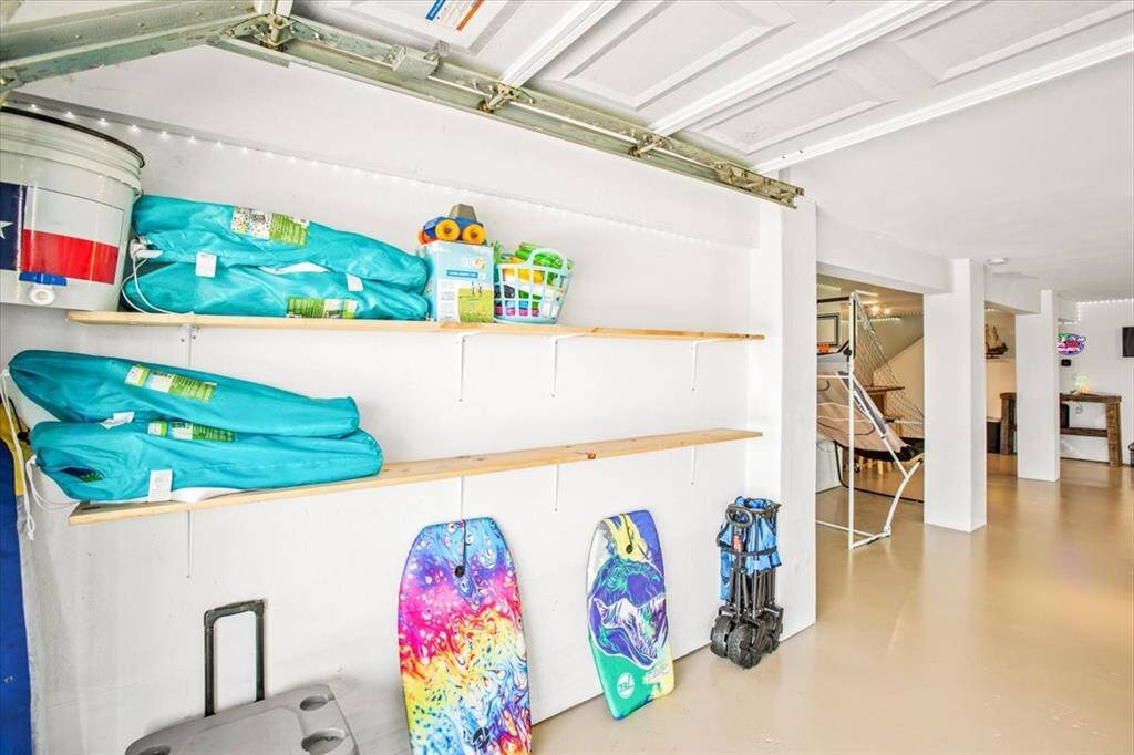 This is a spacious and well-lit lower level with ample shelving for storage. It features a clean and polished floor, and there's direct access to the home's interior via a staircase, suggesting a versatile space that could serve multiple purposes .