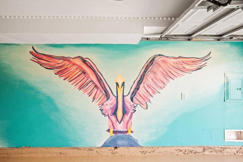 This room features a large, vibrant mural of a bird with outstretched wings on the wall, adding a unique artistic touch to the space.