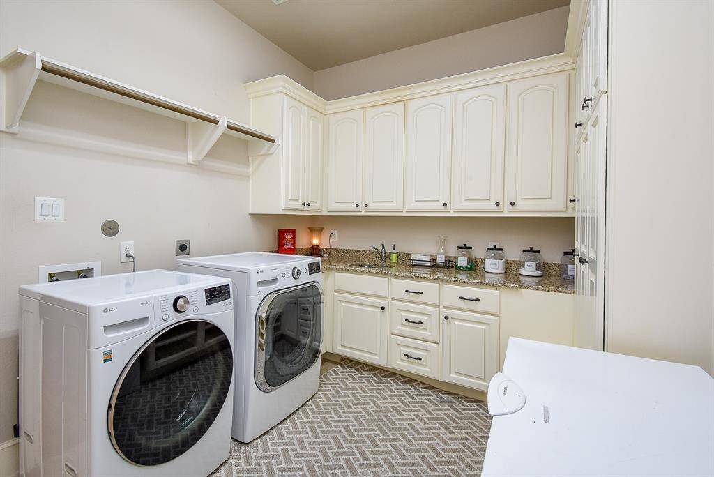 Large laundry room with a sink, granite counter top and cabinets.