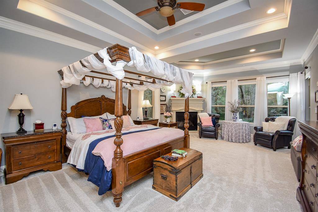 Stunning primary bedroom with sitting area, fireplace, tray ceiling and access to the patio.
