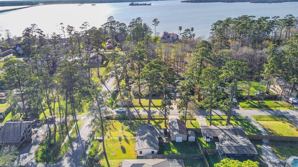 This aerial photo showcases a tranquil neighborhood with lush trees and a scenic view of Lake Houston. The area features well-spaced homes, offering a serene and picturesque living environment.