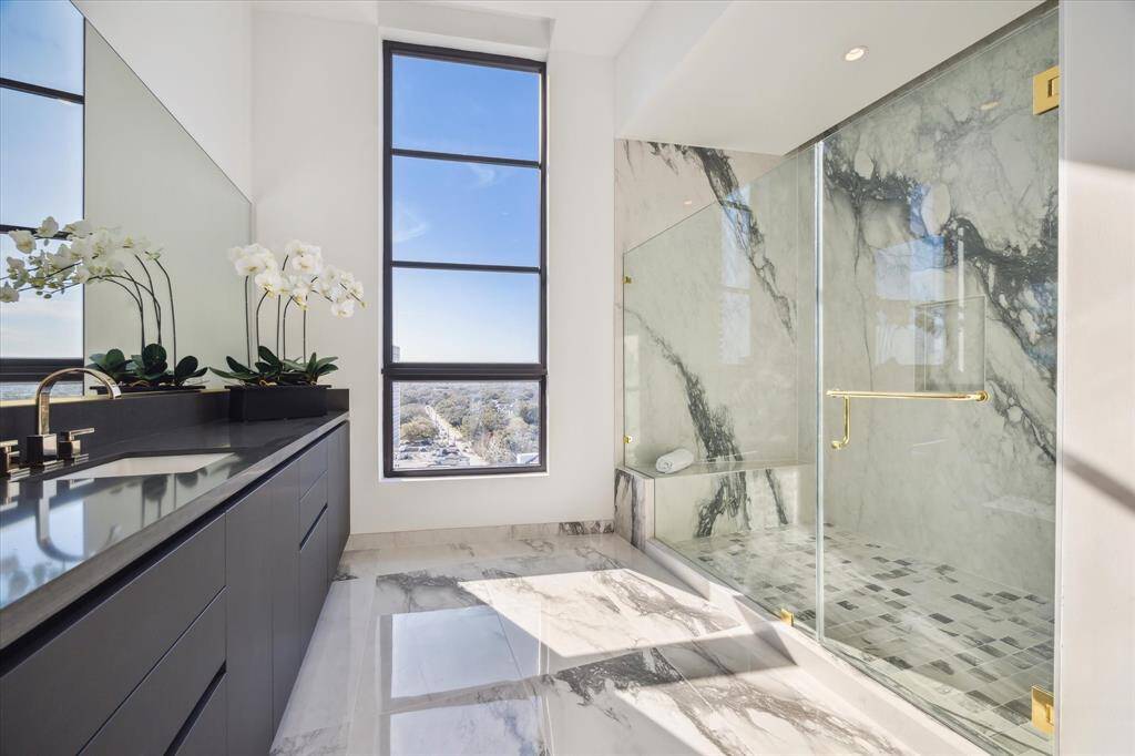 Both Primary Baths feature oversized luxurious showers with stunning slab walls creating striking visual statements. The frameless glass doors, accented with elegant gold details, enhance the modern sophisticated feel, elevating your daily routine into a spa like experience.