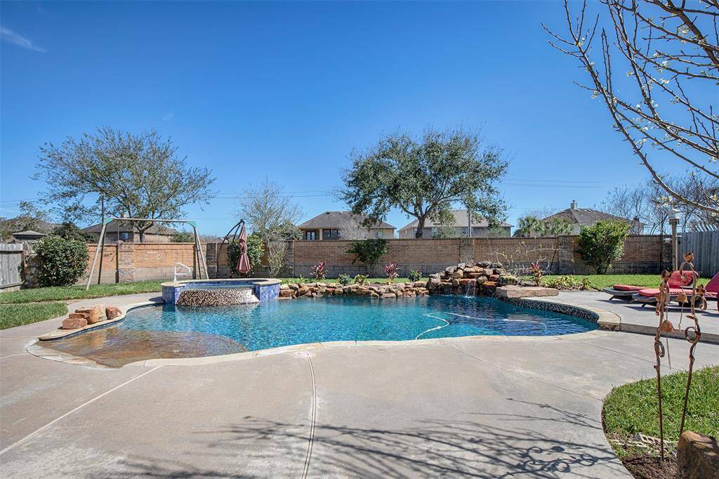 This backyard oasis features a stunning pool with a cascading waterfall and a relaxing spa, creating the perfect retreat for both entertainment and relaxation.