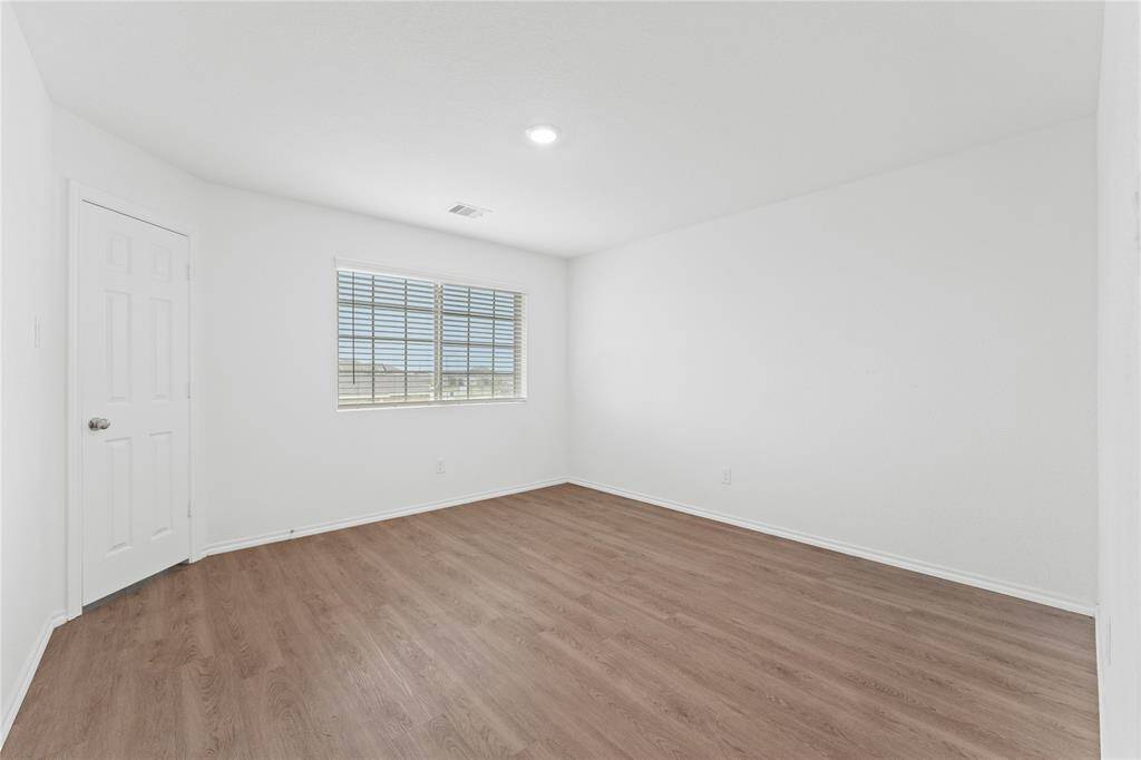One of the bedrooms - Features a bright window, light walls, and wood-like flooring, offering a clean and versatile space.