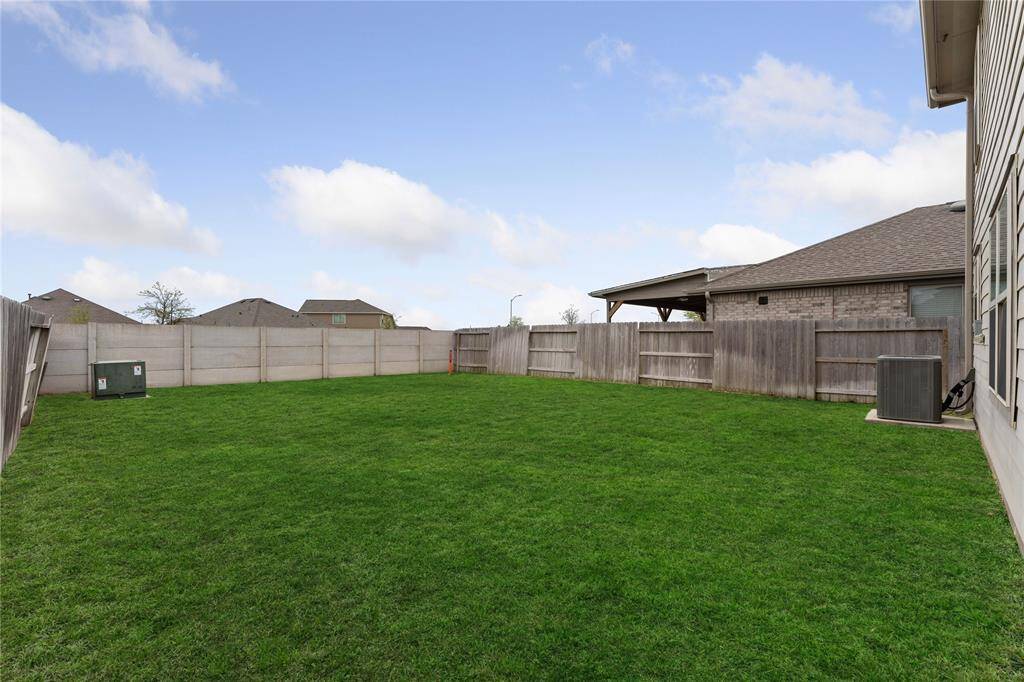 Spacious fenced backyard with a well-maintained lawn, offering privacy and ample space for outdoor activities or gardening.