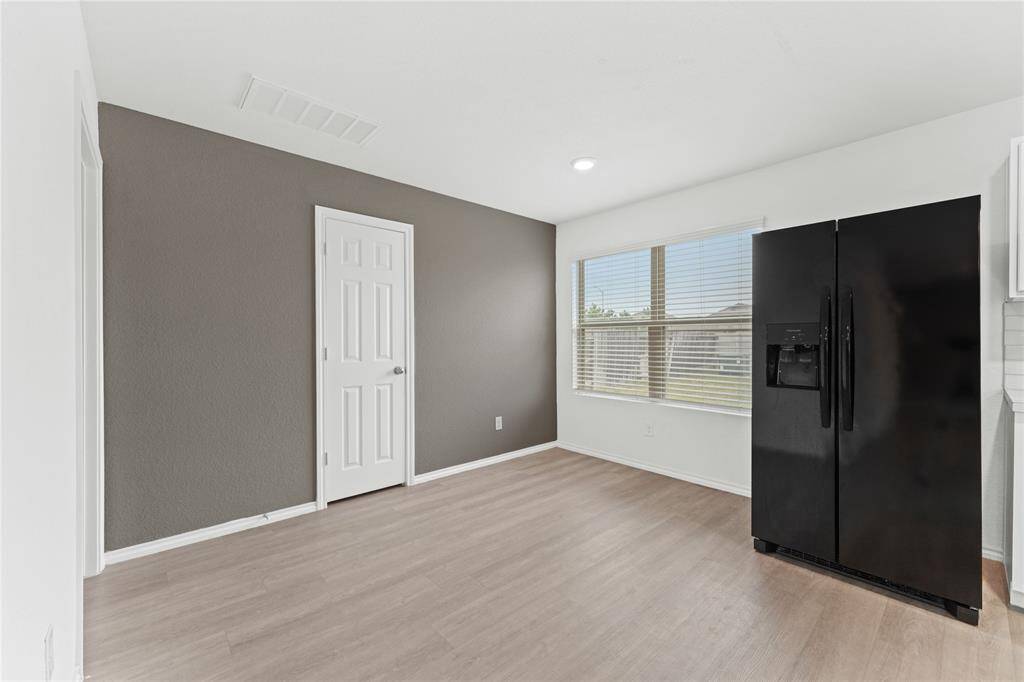 Wood-look flooring, a large window providing natural light, and a feature wall painted a darker color, offering a modern and inviting space.