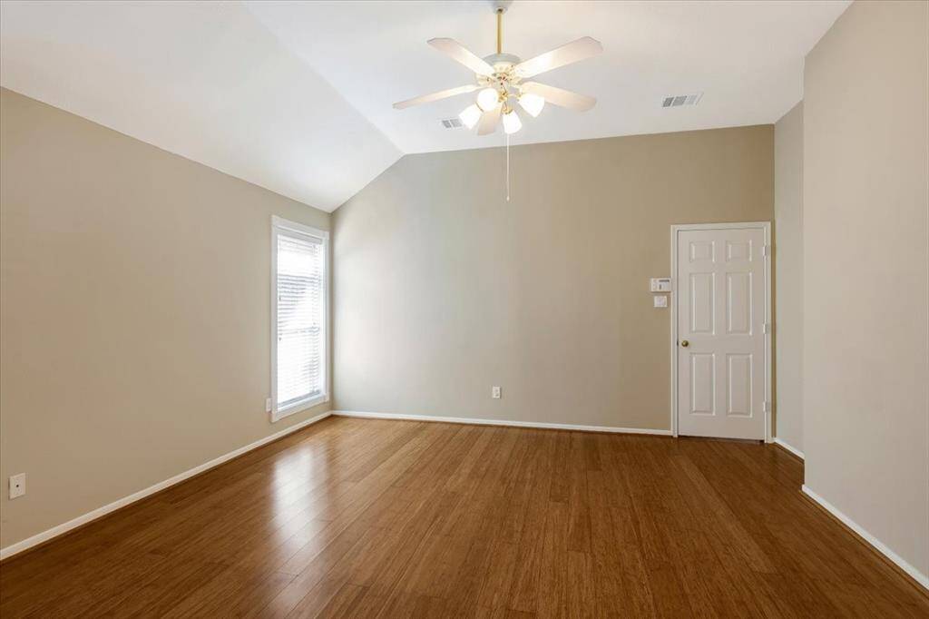 The primary bedroom boasts stunning bamboo flooring, a soaring high ceiling, and a ceiling fan for comfort and elegance.