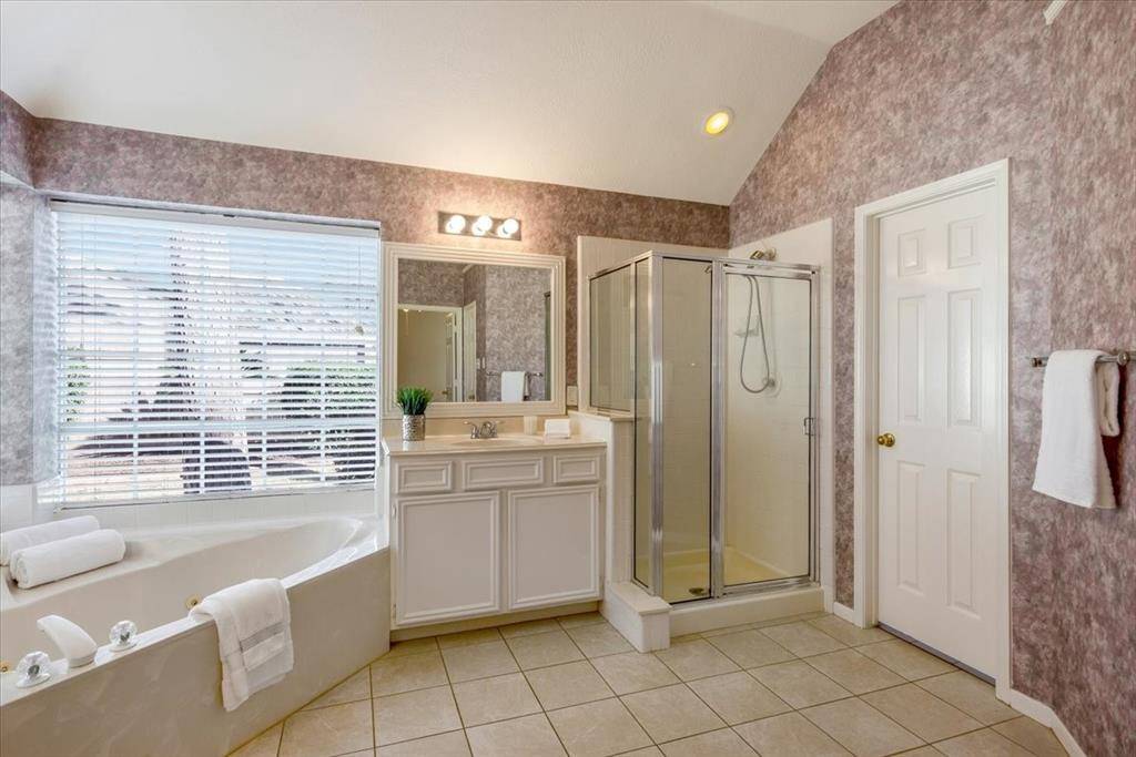 Spacious primary bath with a jacuzzi tub and glass-enclosed shower.
