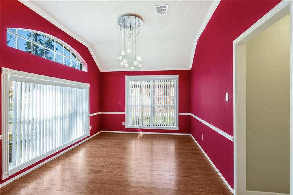 Elegant front-facing dining room filled with natural light from multiple windows, showcasing a stylish designer light fixture and sophisticated wall colors for a warm and inviting ambiance.