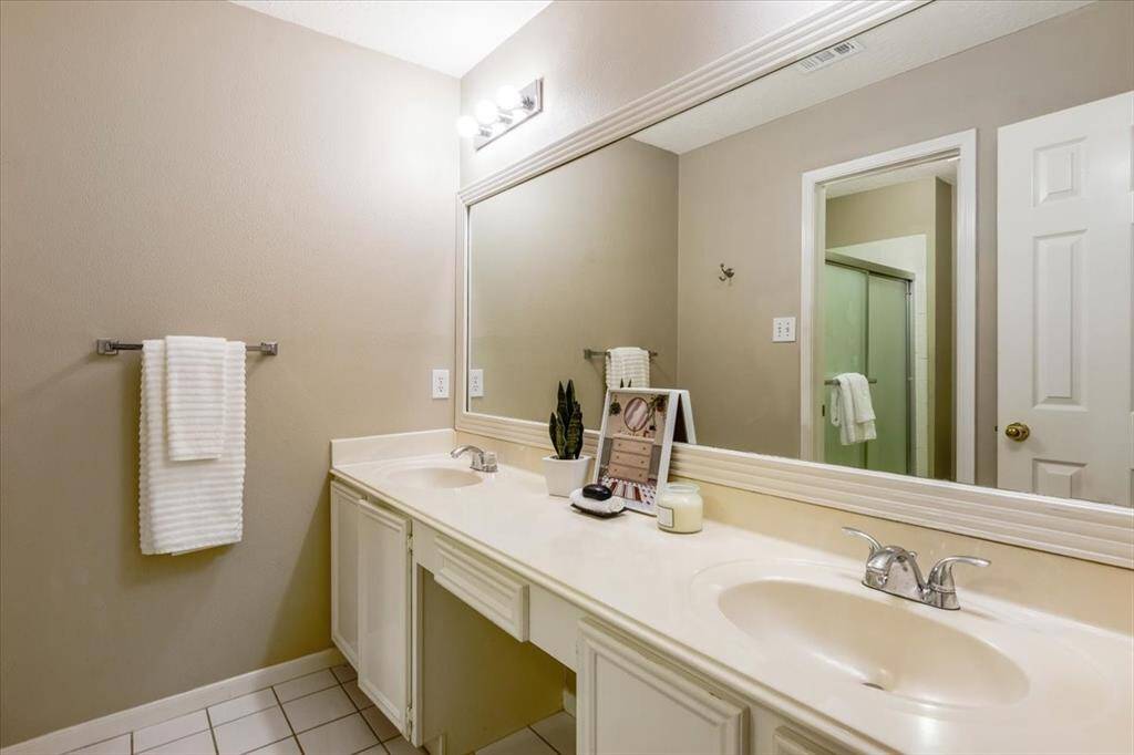 The secondary bathroom features dual sinks and a spacious vanity area, offering plenty of counter space and functionality for everyday use.