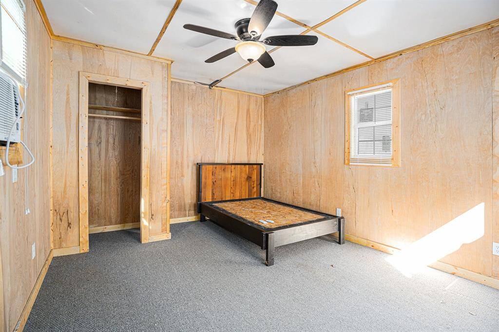 The additional building features paneled walls and a carpeted floor. The windows allow natural light into the space. The building is heated and cooled, making it suitable for year-round use as a hobby area, office, or other versatile space.