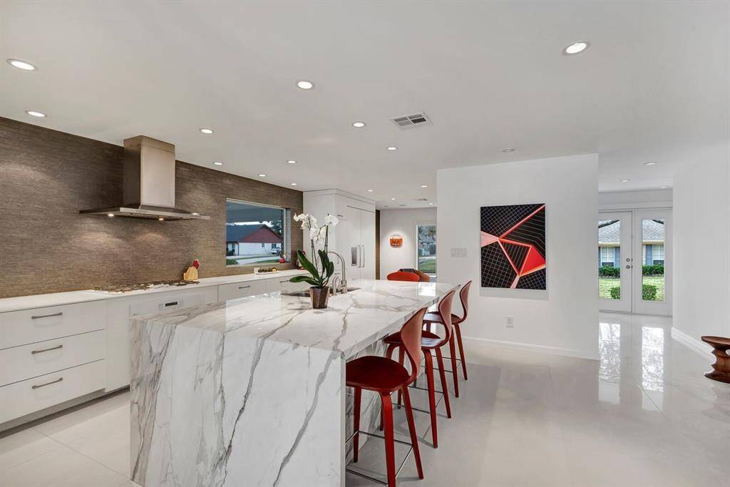 Standing as a centerpiece of the kitchen, the expansive island is crafted from the now-rare Calcutta Gold marble, beautifully book-matched at every joint. The island features a comfortable overhang for counter-height barstool seating, offering a stylish and functional space for casual meals and conversation. Every appliance is either built-in or integrated with solid surface panel fronts, including the dishwasher, refrigerator, and freezer, which blend harmoniously with the cabinetry.