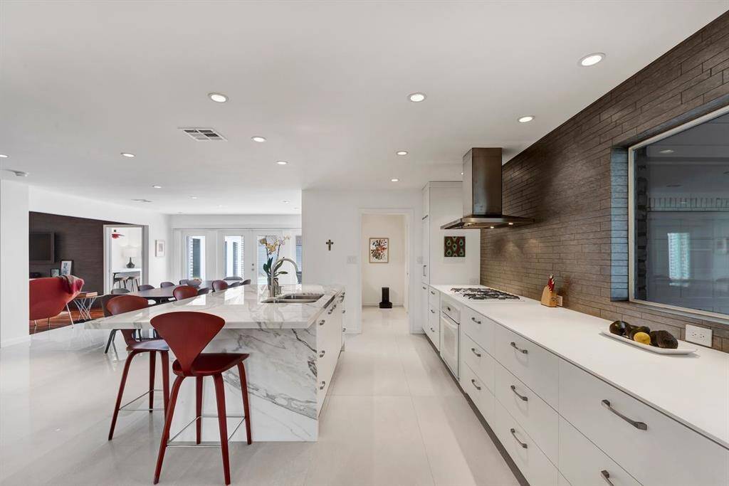Crafted with precision, this sleek, modern kitchen showcases a luxury interlocking porcelain tile backsplash, adding texture and depth to the space. Thoughtfully designed with custom 26-inch deep drawers instead of traditional cabinets, the expansive 30-inch deep countertops enhance both functionality and elegance, creating a streamlined and polished aesthetic.