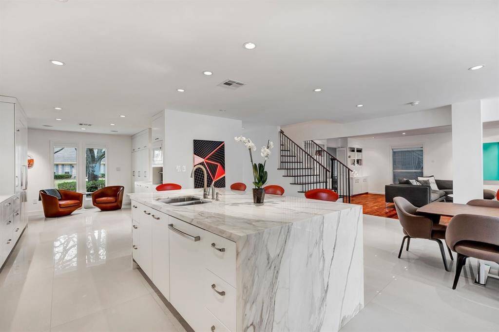 Unparalleled in its elegance, the now-rare Calcutta Gold marble single-slab island serves as a breathtaking focal point, with perfectly book-matched veining cascading down the waterfall edge. From this vantage point, the open sightlines extend seamlessly, showcasing the staircase leading to all four bedrooms, including the primary suite, embodying the owner's vision of modern, clean lines and unobstructed flow throughout the home.