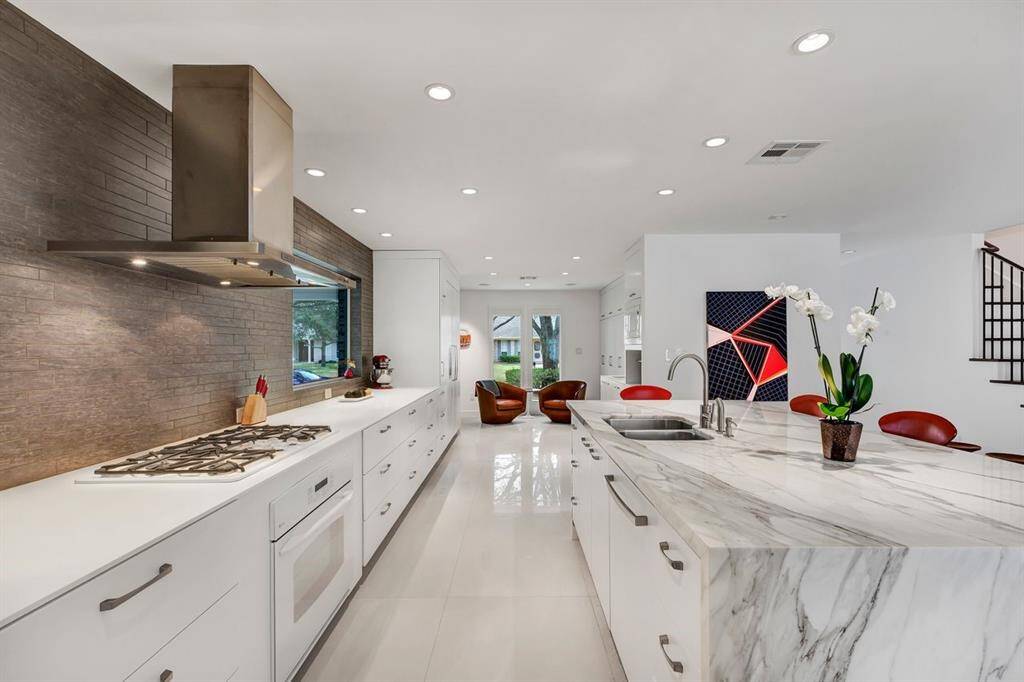 The heart of the home, this beautifully remodeled kitchen blends high-end materials and custom cabinetry. Featuring Corian solid surface countertops and custom cabinet and drawer fronts, creating a seamless and refined aesthetic. A large picture window above the workspace enhances natural light, offering a beautiful connection to the outdoors while complementing the clean and polished design.