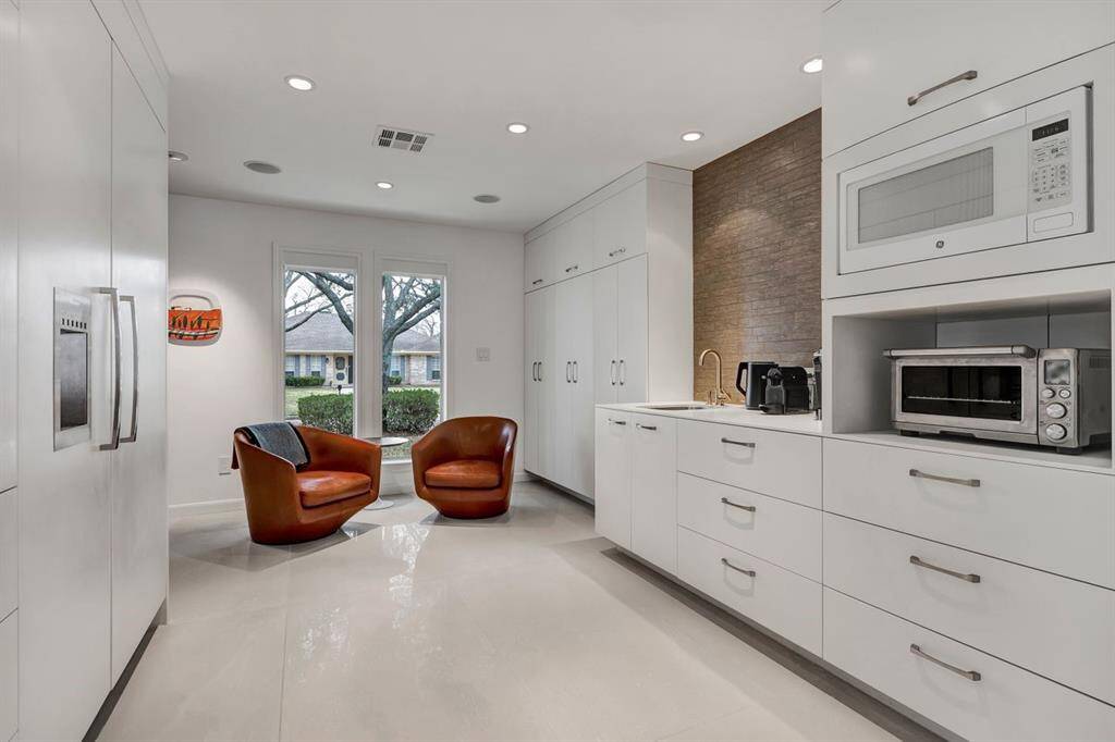 At the end of the kitchen, a cozy nook provides the perfect space for sipping morning coffee or unwinding with a glass of wine, offering a serene retreat within the home. The bar sink area functions as a coffee bar, with storage below to keep essentials within easy reach. Floor-to-ceiling pantry cabinets were custom-designed to maximize visibility and access.