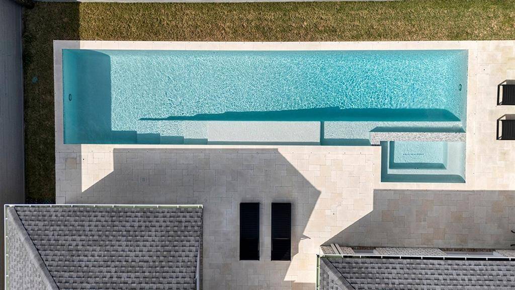 Designed for both function and style, the stunning 48-foot lap pool features oversized steps leading to a spacious tanning shelf with three bubblers, adding ambiance and fun. A built-in seat near the deep end and spa creates the perfect spot for guests to relax and connect, offering a seamless blend of luxury and leisure.