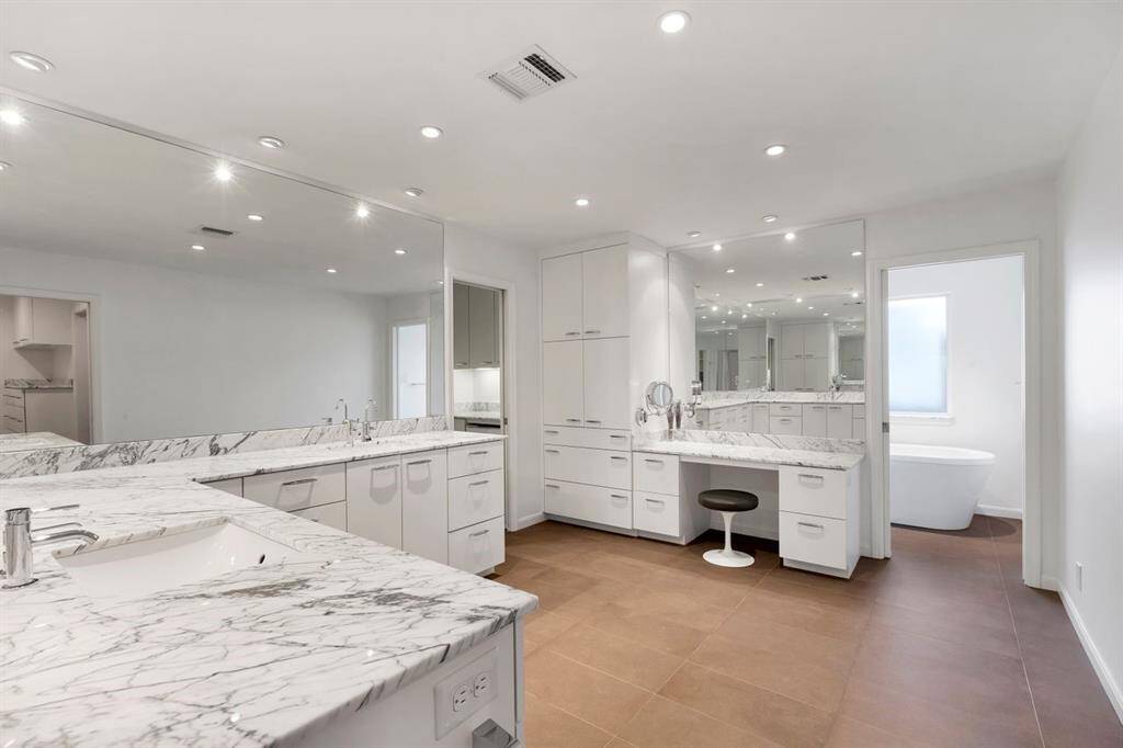 Sophisticated and serene, the modern owner's bath features a built-in makeup vanity with a premium Bering’s Hardware mirror. Durable porcelain flooring flows seamlessly throughout. A private pocket door leads to a serene soaking tub and shower, while the left doorway opens to a private water closet.
