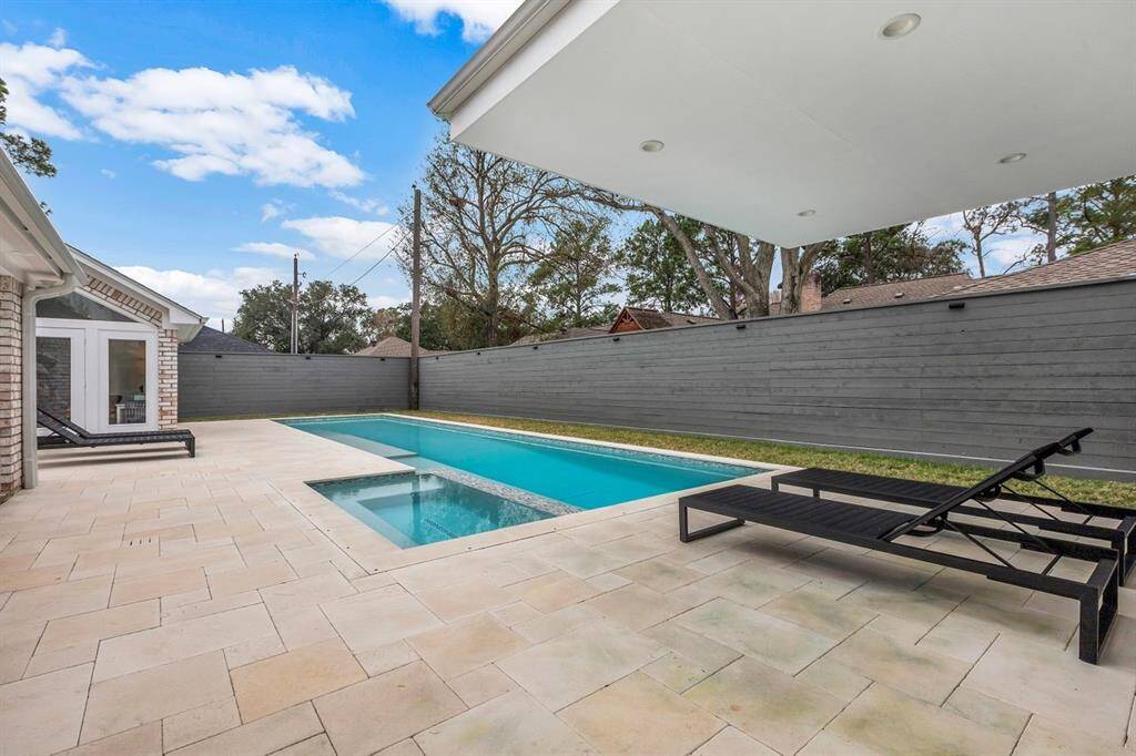Luxury and privacy define this spa-like retreat. The pool is framed with elegant limestone coping, while over 900 square feet of limestone pavers create a spacious deck perfect for entertaining. The backyard’s sleek gray horizontal plank fence, accented by solar-powered fixtures, creates a serene ambiance.