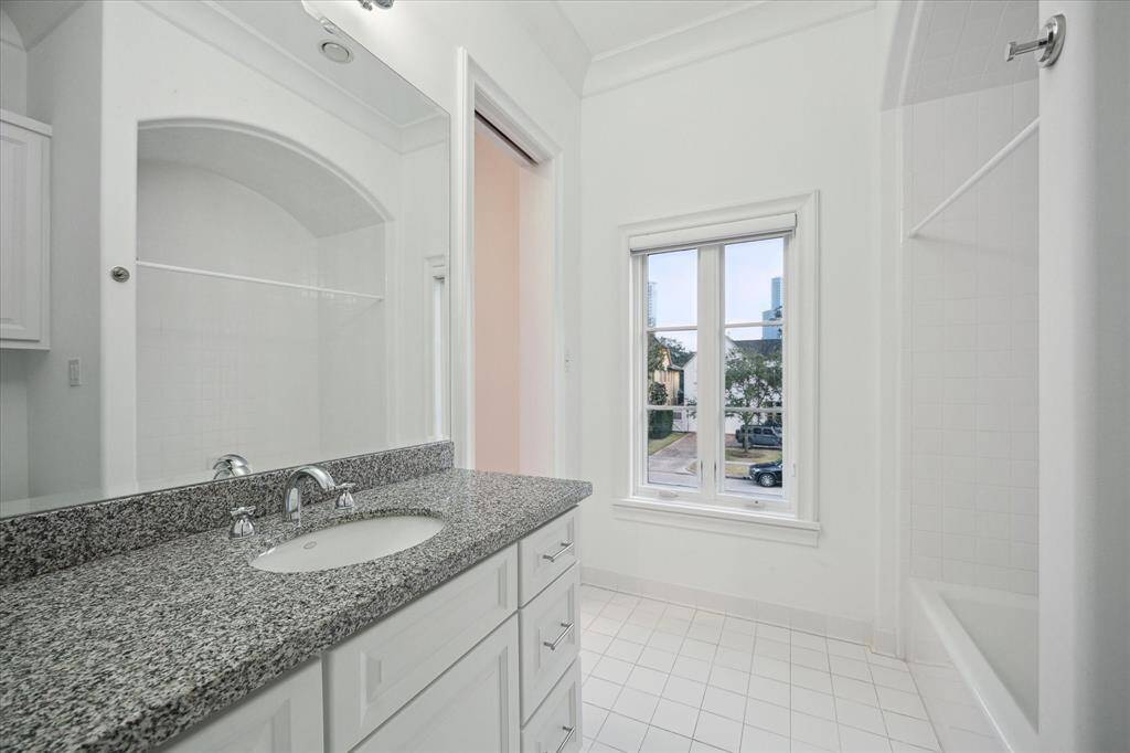 Bright and inviting bathroom with elegant granite countertop and a spacious tub and shower combination.