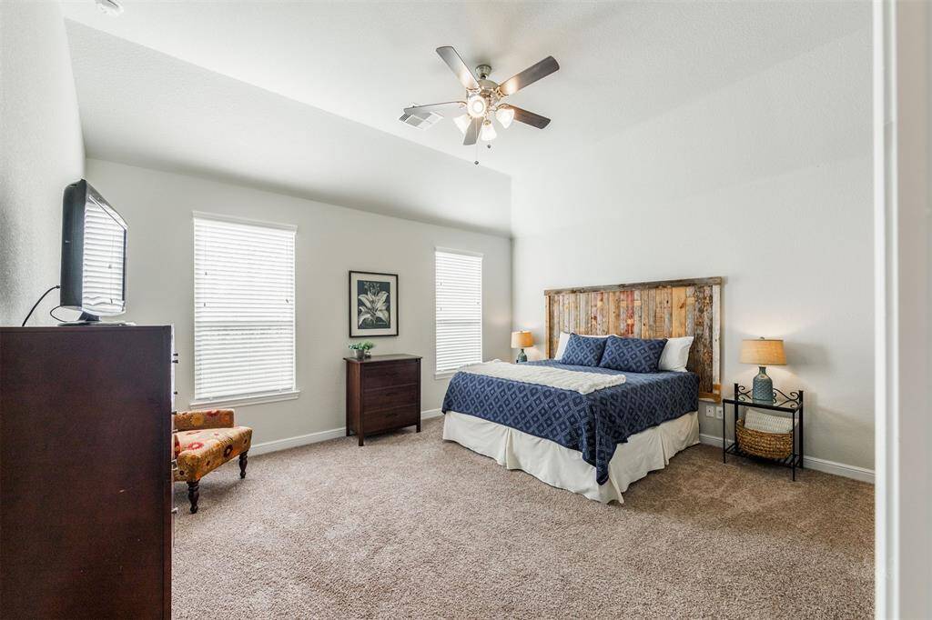Come home and unwind in this lovely primary suite featuring a high angled ceiling and carpet for comfort! Enjoy the warm and relaxing environment with plenty of space for your king size bed, dresser and chairs and table for a reading nook.