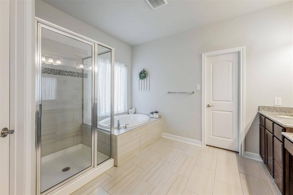 Step into this relaxing primary bath featuring an extended double sink granite vanity, make up vanity, garden tub and a large enclosed shower with tile surround!