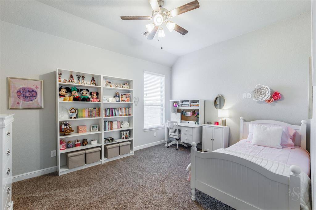 This secondary bedroom features a high angled ceiling, a window with blinds, carpet for comfort and provides plenty of room for a bed and your bedroom furnishings including a student desk.