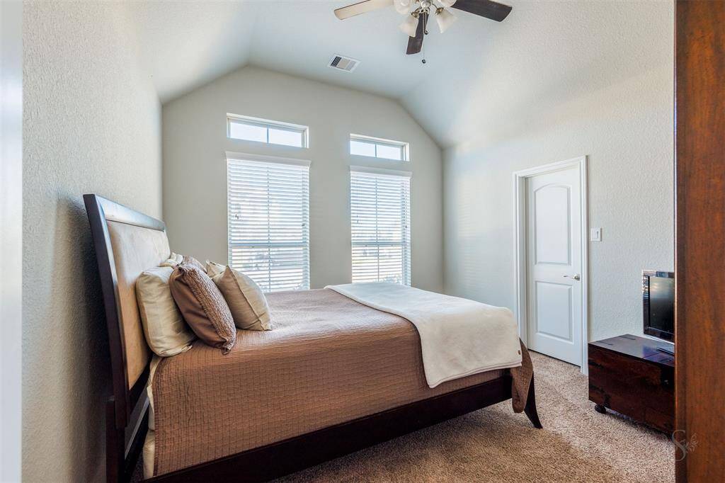 This secondary bedroom features a high angled ceiling, windows with blinds, carpet for comfort and provides plenty of room for a bed and your bedroom furnishings including a student desk.