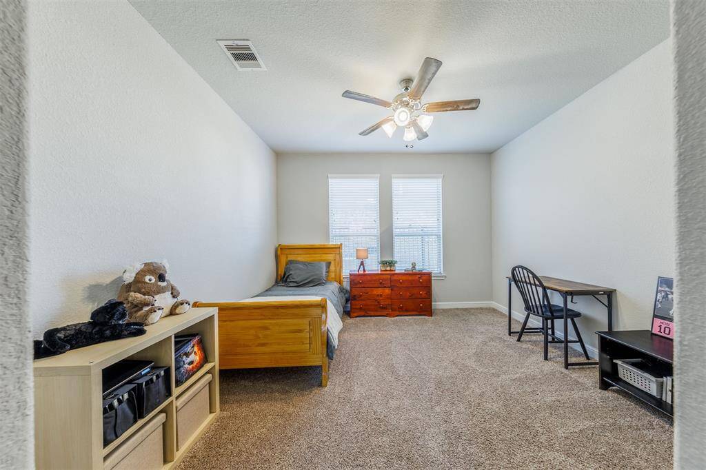 This secondary bedroom features a high ceiling, windows with blinds, carpet for comfort and provides plenty of room for a bed and your bedroom furnishings including a student desk.