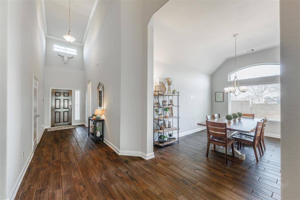 Stepping through the front door, you're greeted by high ceilings with crown molding and beautiful wood-look tile flooring. Just beyond, the formal dining room boasts an arched entry, high angled ceiling and is perfect for hosting memorable gatherings in style.