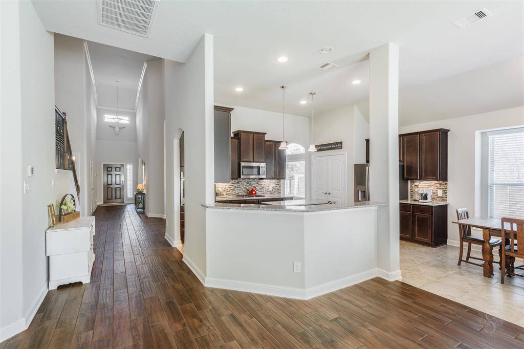 This bright and airy living space boasts an open floor plan where the family room, kitchen and breakfast room  all flow together seamlessly. With natural light pouring in and gorgeous wood-look tile flooring throughout, it’s the perfect spot for gathering, entertaining, or just relaxing with your family.