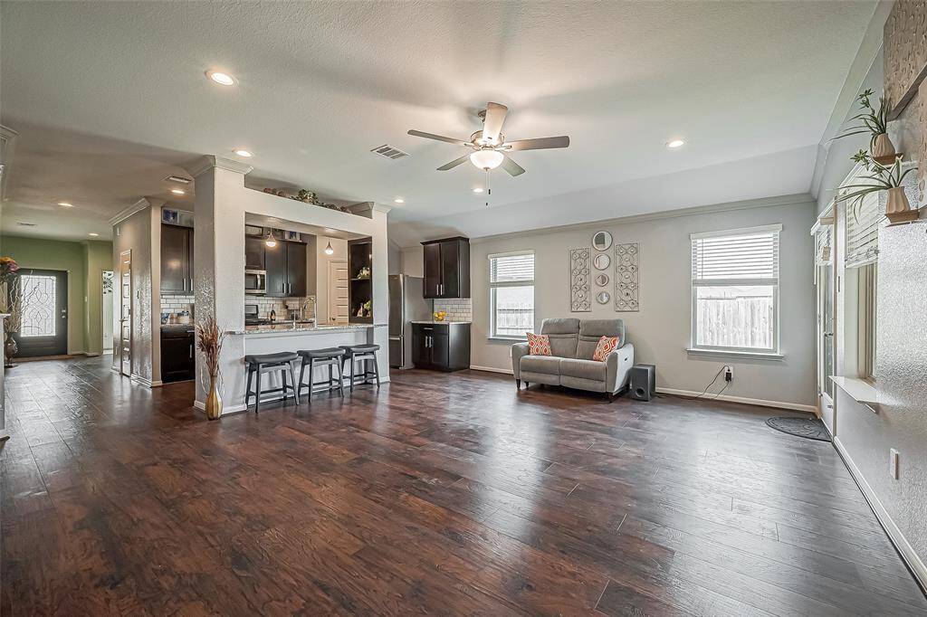 This spacious open-concept living area features beautiful laminate wood-like floors, a modern kitchen with a large island and bar seating. Notice the ample natural light from multiple windows. This is the ideal space for entertaining family and friends.