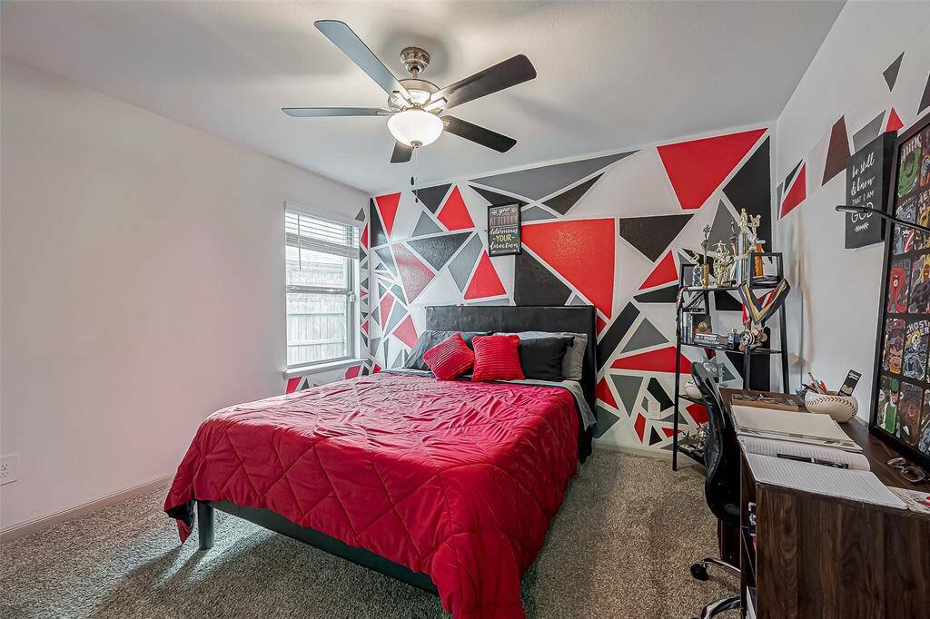 This room features a modern design with a striking geometric accent wall in red, black, and white. This room has a  ceiling fan for extra comfort.