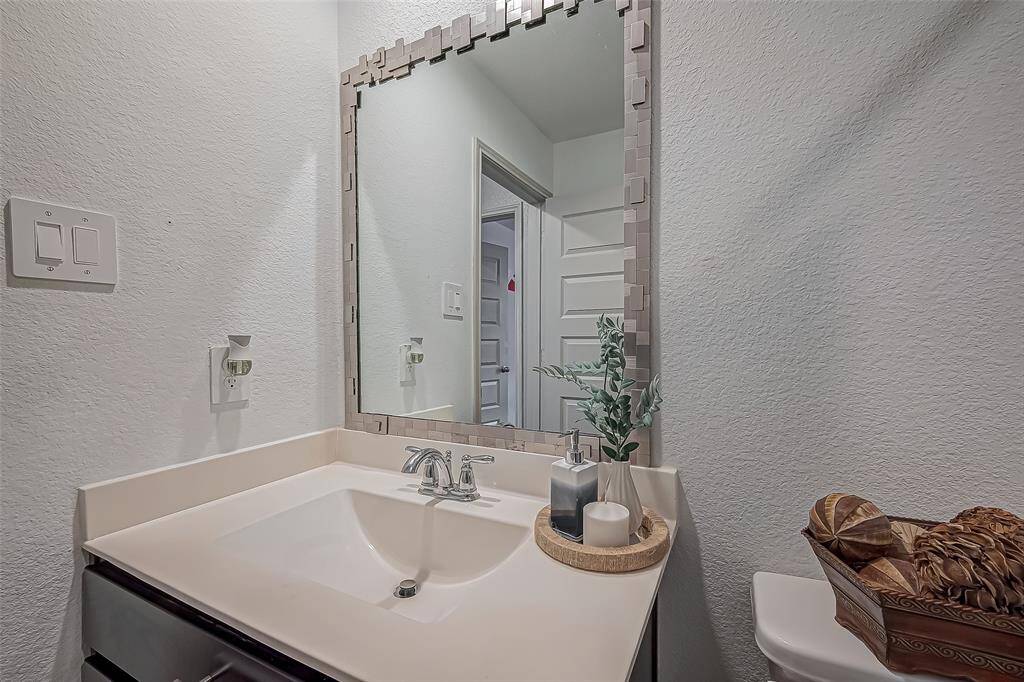 This photo shows a modern bathroom with a stylish vanity. It features a sleek sink with a chrome faucet, a decorative framed mirror.