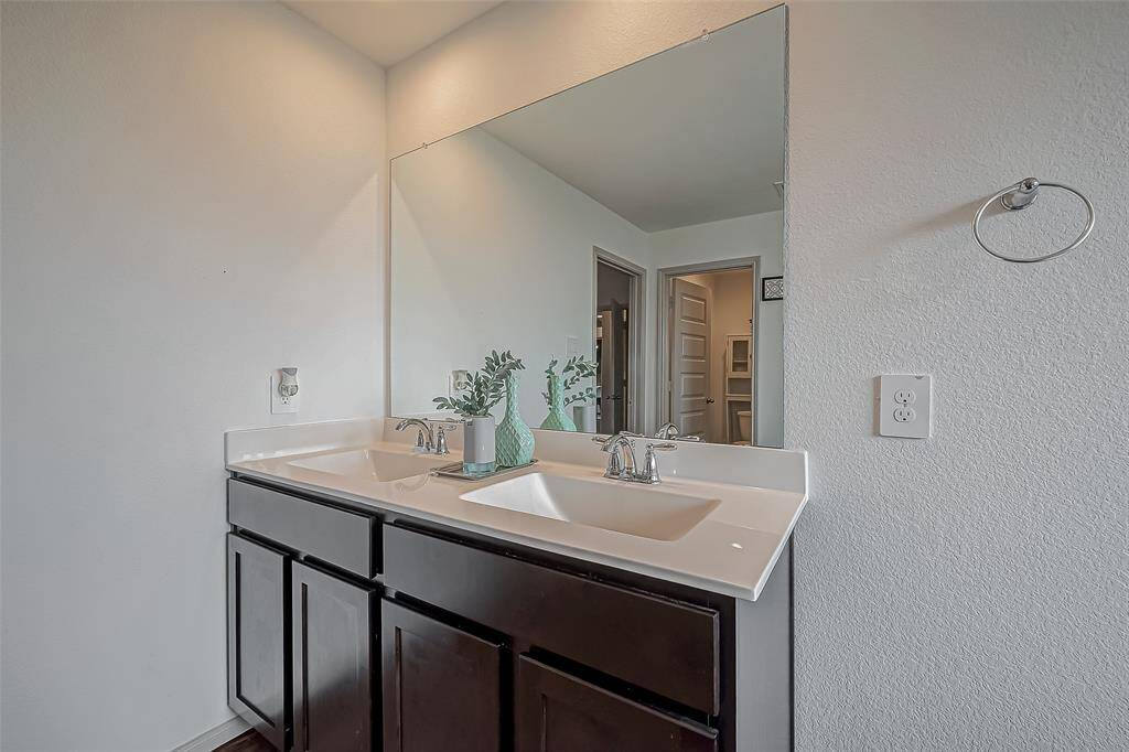 This bathroom features a sleek double vanity with dark wood cabinets, a large mirror, and modern fixtures. The space is bright and functional, perfect for a contemporary home.