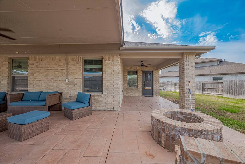 Wow! Take a look at this spacious covered patio with comfortable seating, a ceiling fan, and a brick fire pit, perfect for outdoor relaxation and entertaining. The area is surrounded by a fenced yard, providing privacy and a cozy atmosphere.