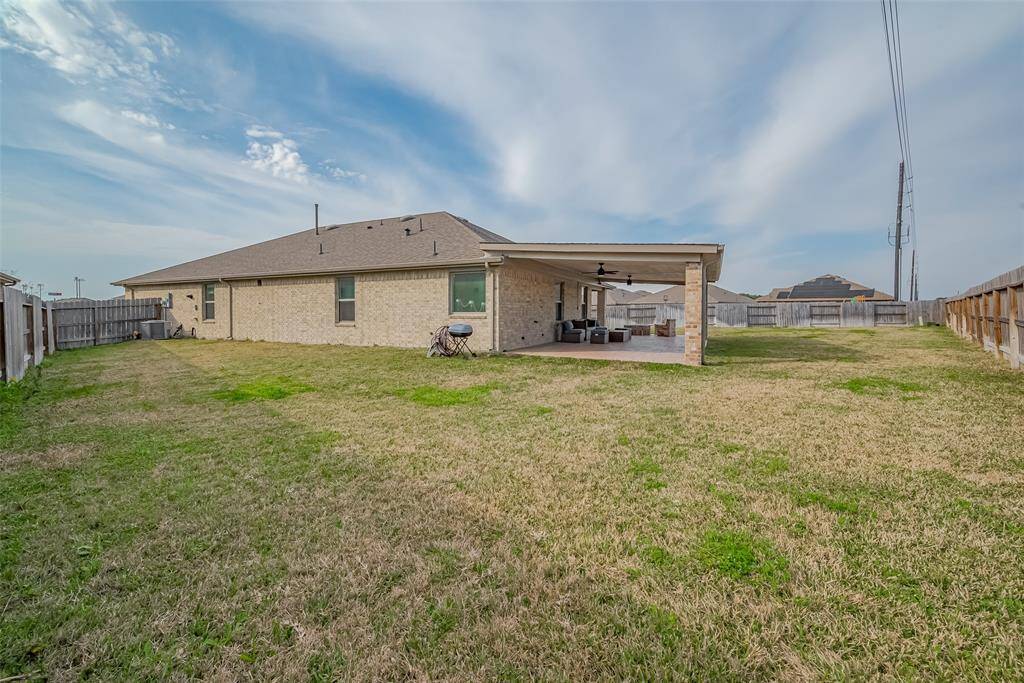 Spacious backyard with a large covered patio, perfect for outdoor entertaining. The area is fenced for privacy and has terrific lawn space.