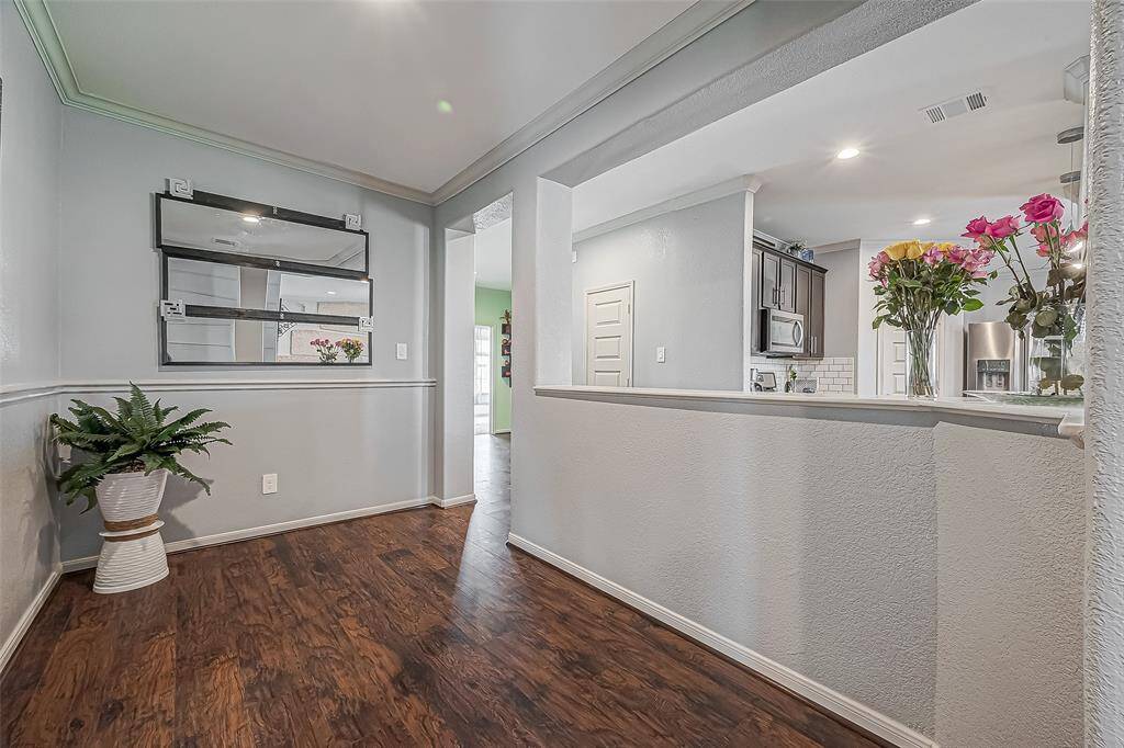 This photo showcases a welcoming dining space with laminate wood like flooring and soft gray walls. Bright lighting enhances the inviting atmosphere.