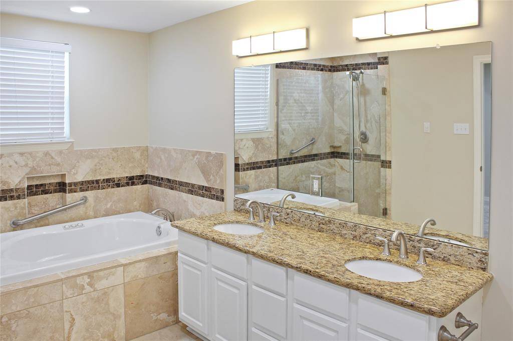 Luxurious primary bathroom featuring dual sinks, a spacious tub, and a standalone shower.