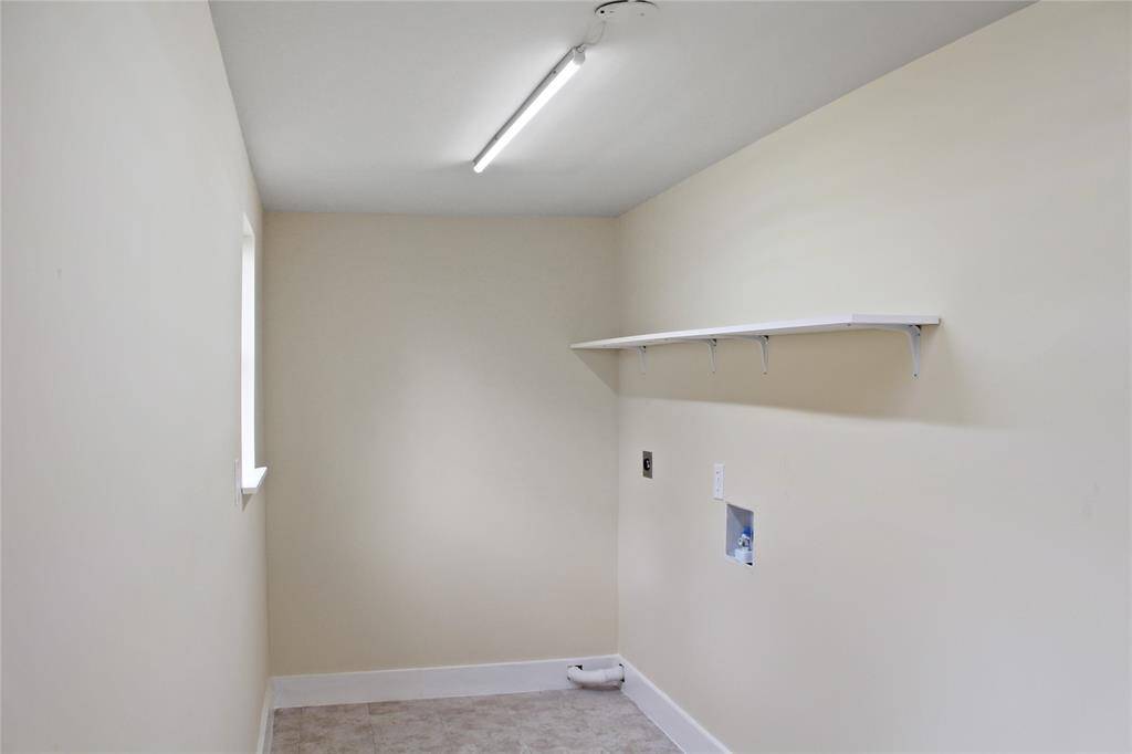 Spacious laundry room with convenient shelving and ample natural light.