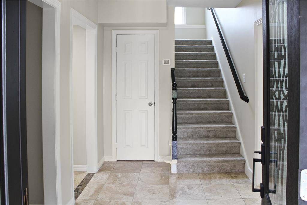 Welcome to a bright and inviting entrance featuring elegant tile flooring and a stylish staircase, setting the tone for the rest of the home.