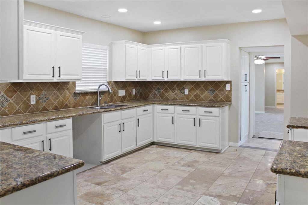 Elegant kitchen featuring sleek white cabinets and luxurious granite countertops.