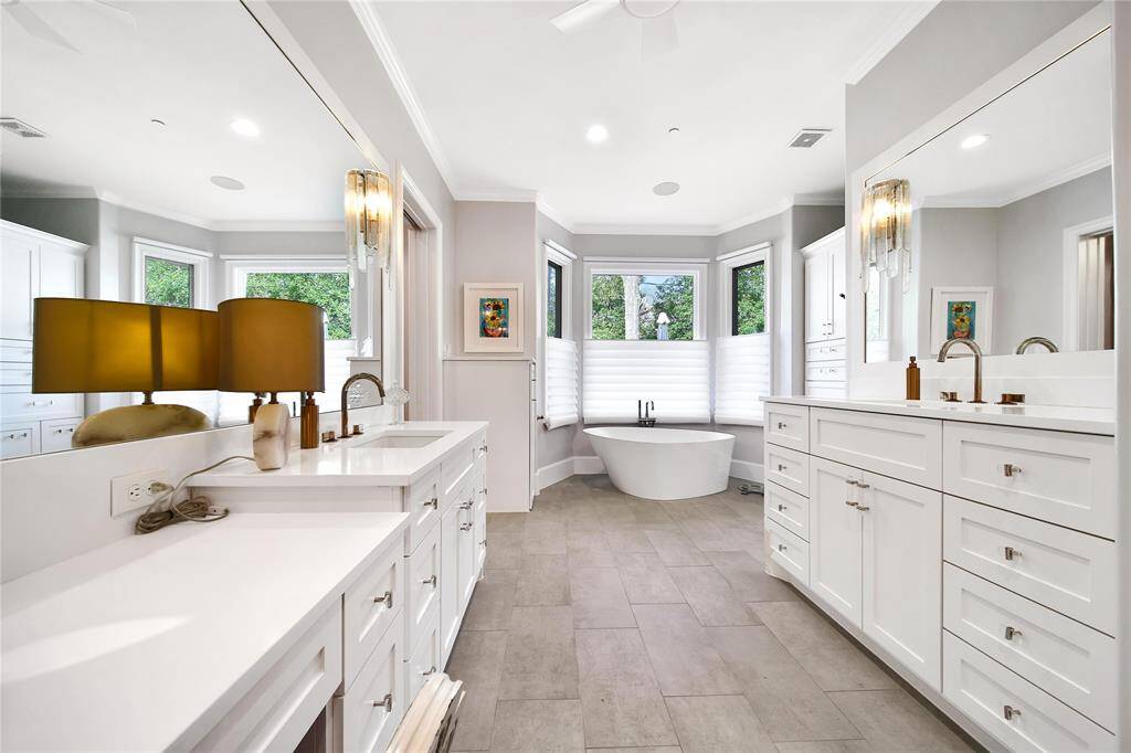 Expansive primary bathroom with updated sinks, countertops, hardware, commodes, faucets, lighting, shower finishes, and flooring.