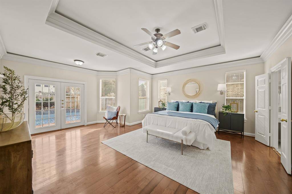 The primary suite is GORGEOUS! It has coffered ceilings, hardwood flooring and French doors that open up to the pool and backyard.