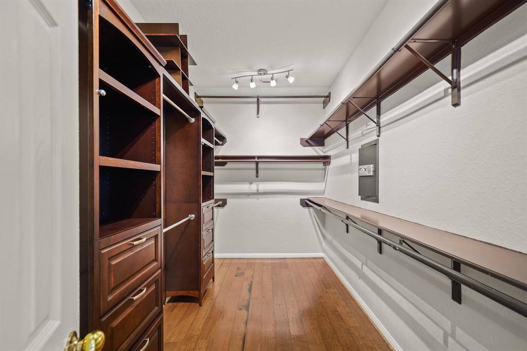The primary closet has custom built-ins, hardwood flooring and a built-in wall safe.