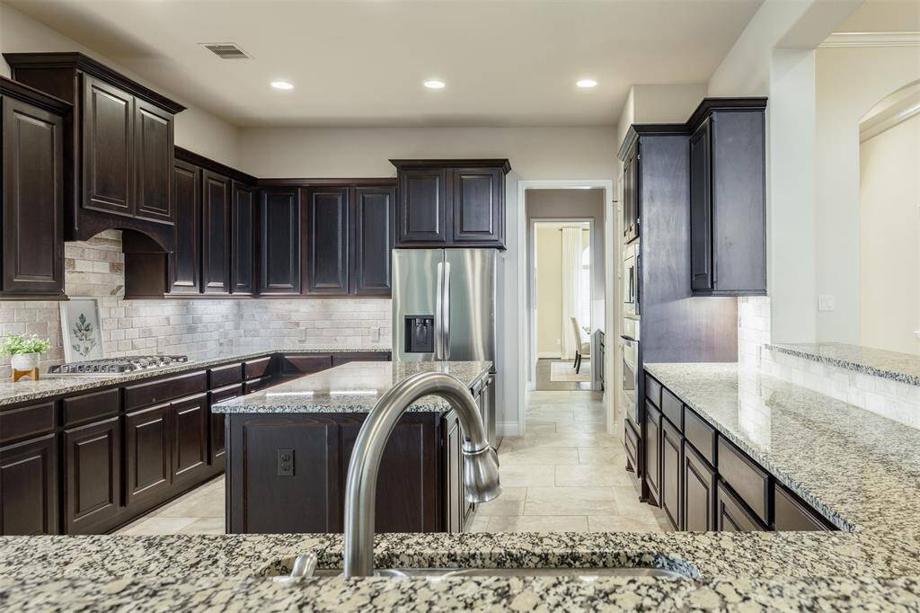 A kitchen fit for a Chef! This sensational designer kitchen showcases gorgeous granite countertops including a central island, stainless steel appliances, gas cooktop and custom backsplash highlighted by recessed and under cabinet lighting.